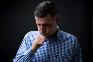 Portrait of a man coughing over black background